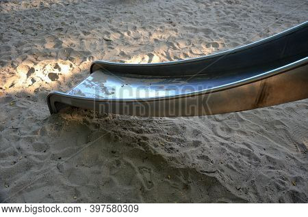 Stainless Steel Slide And Swings On The Playground In The Park In Gray Pebbles