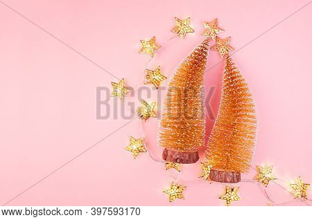 Luxury New Year Gold Shimmer Decor With Christmas Tree, Stars, Glowing Lights On Soft Light Pink Bac