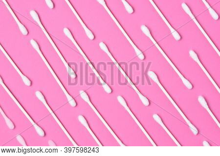 Cotton Swabs lined up on a pink background.