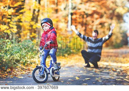 Little Kid Boy Learning Moving On Bicycle. His Father Teaching His Son Biking. Happy Man And Child. 