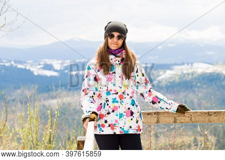 Happy Tourist Girl In Colored Jacket Standing On Observation Deck In Mountains Covered Snow
