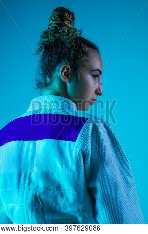 Posing. Professional Female Judoist In White Judo Kimono Practicing And Training Isolated On Blue Ne
