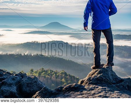 Man Watch Thick Mist In Valley From Rocky View Point In Mountains. Hiker Climbed Up Alone To Exposed