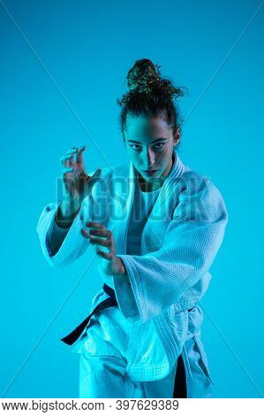Attack. Professional Female Judoist In White Judo Kimono Practicing And Training Isolated On Blue Ne