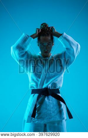 Posing. Professional Female Judoist In White Judo Kimono Practicing And Training Isolated On Blue Ne