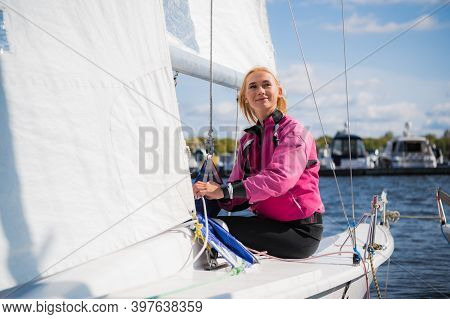A Young Female Sailing Athlete Sets A Genaker Sail On Her White Sports Yacht To Go To A Regatta