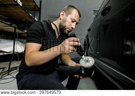 Car Detailing Series - Polishing Of Black Car. Auto Service Worker, Wearing Black Clothes, Puts Spec