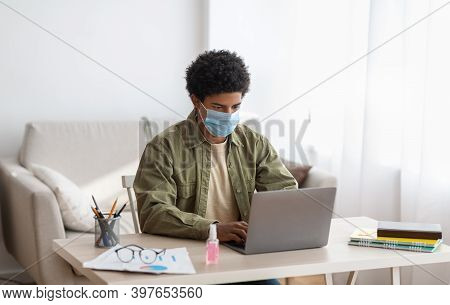 Web Based Learning During Covid-19 Pandemic. Teenage Male Student In Medical Mask Attending Online C