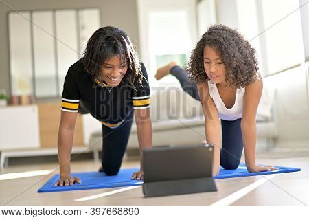 Mother and daughter doing fitness exercices at home