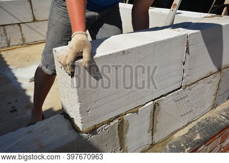 A Building Contractor Is Building A Wall Lying Autoclaved Aerated Concrete (aac) Blocks Over Brick F