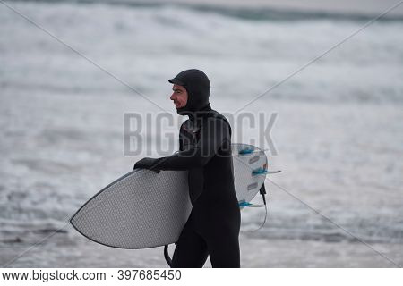 Arctic surfer going by beach after surfing