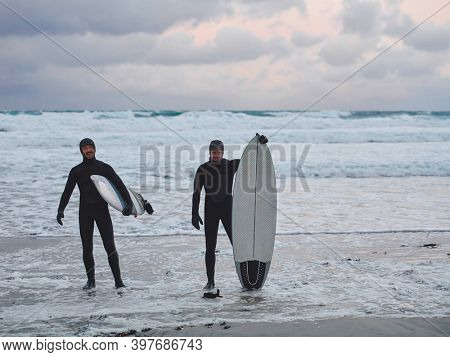 Arctic surfers going by beach after surfing
