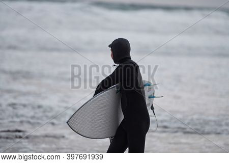 Arctic surfer going by beach after surfing