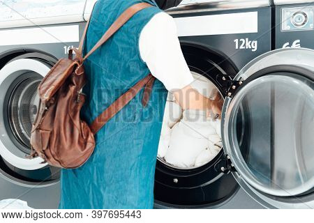 Unrecognizable Person Putting Dirty Clothes In The Drum Of The Washing Machine In A Public Laundry. 