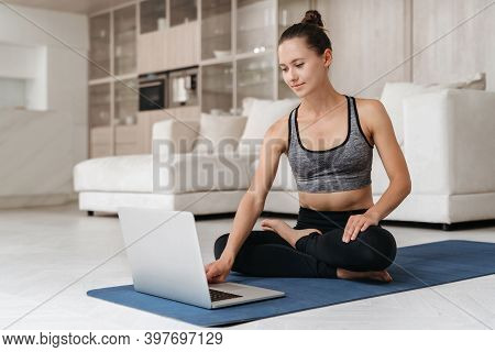 Smiling Young Fit Woman Learning Yoga Exercises Sitting On Mat In Lotus ...