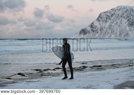 Arctic surfer going by beach after surfing