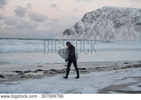 Arctic surfer going by beach after surfing