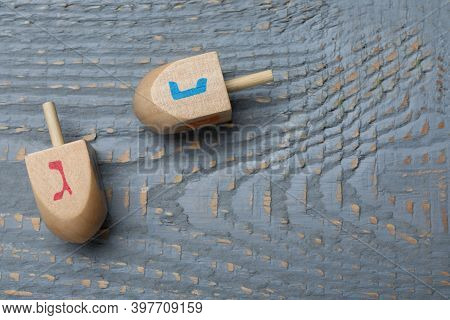Hanukkah Traditional Dreidels With Letters Nun And Gimel On Grey Wooden Table, Flat Lay. Space For T