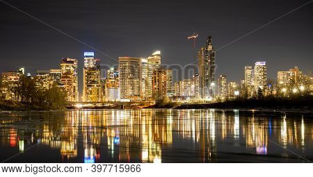 Downtown Calgary Office Building Lights Reflecting On The Bow River At Night.