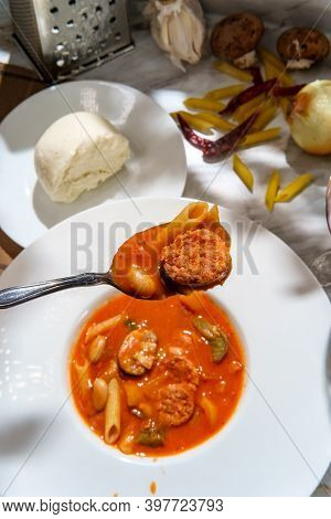 Creamy Italian Sausage Soup With Mozzarella Cheese Onions And Peppers Served With A Glass Of Red Win