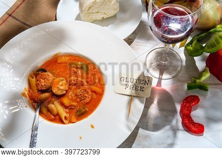 Creamy Italian Sausage Soup With Mozzarella Cheese Onions And Peppers Served With A Glass Of Red Win
