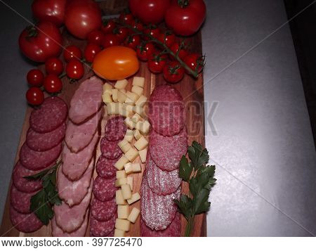 Slicing Smoked Sausage Of Four Varieties With Cheese And Red And Yellow Tomatoes And Cherry Tomatoes