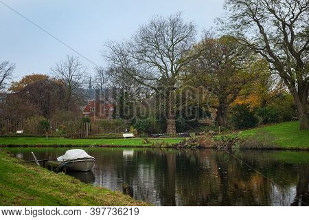 View Over The Canal To The Botanical Garden In Leiden, Netherlands With The Boat In Foreground