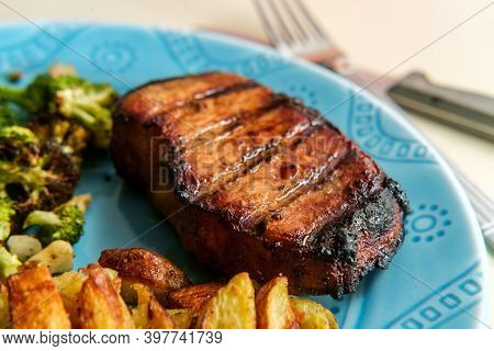 Marinated Char-grilled Pork Chops With Grill Marks Side Of Home Fries And Broiled Broccoli