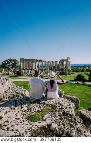 A Couple Visit Greek Temples At Selinunte During Vacation, View On Sea And Ruins Of Greek Columns In