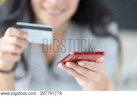 Woman Holding Bank Card And Phone In Her Hands Close-up. Online Shopping Concept