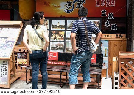 Beppu, Oita, Japan, July 12, 2017 : A Young Married Couple View Photos On A Street In The Japanese C