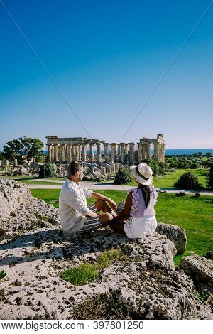 A Couple Visit Greek Temples At Selinunte During Vacation, View On Sea And Ruins Of Greek Columns In