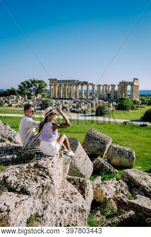 A Couple Visit Greek Temples At Selinunte During Vacation, View On Sea And Ruins Of Greek Columns In