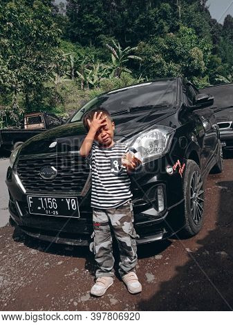Cianjur, West Java, Indonesia, December 3, 2020, Portrait of a boy overheating in front of a black car
