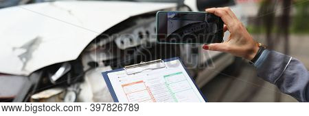 Woman Photographs A Broken Car On Smartphone And Holds Insurance Documents In Her Hands. Damage Asse
