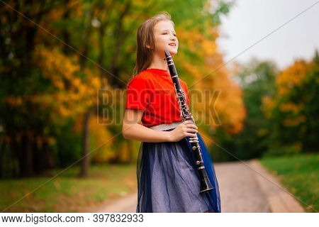 Young Attractive Girl Playing Clarinet, Ebony In Fall Park