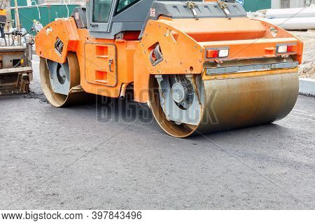 The Metal Cylinders Of The Large Vibratory Roller Roll On The New Road Surface After The Hot Asphalt