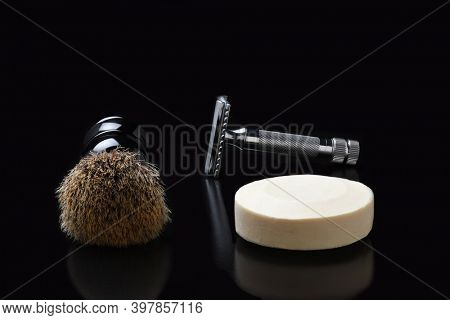Shaving still life. A razor shaving brush and bar of soap on black.