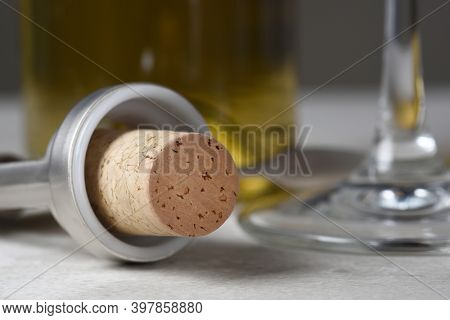 Closeuup of a wine cork in wing style corkscrew with glass and bottle in background.  Shallow depth of field. 