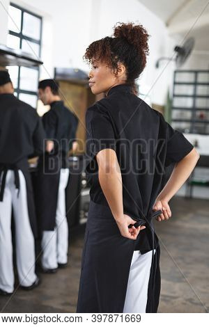 Divserse group of chefs cooking in kitchen. trainee male and female chefs wearing black aprons and preparing before cooking lesson.