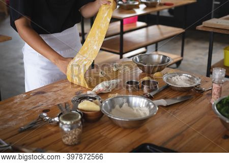 Mid section of chef preparing ravioli with stuffing at restaurant kitchen. food preparation restaurant culinary gourmet