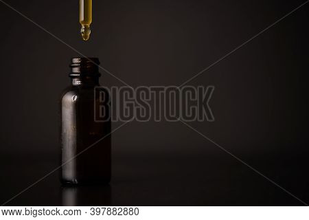Glass Dropper With Black Background And Orange Liquid