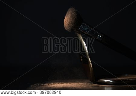 Makeup Brush With Falling Powders On Black Background