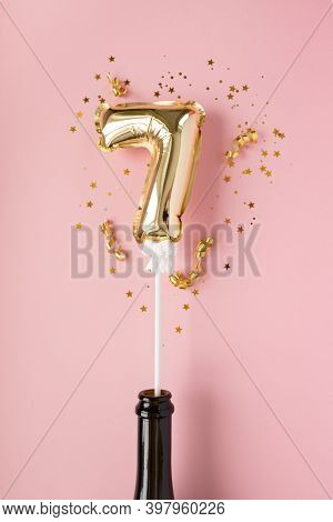 Gold Inflatable Number 7 On A Stick With Gold Confetti On A Pink Background.
