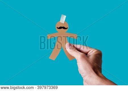 man with a paper man doll in his hand, as a prank for dia de los inocentes, the innocents day, a feast held in spain, hispanic america and philippines equivalent to april fools day, blue background