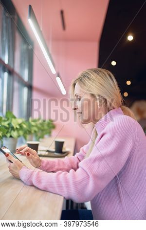Woman On Phone Texting Text Message On Smartphone App Sitting Indoor In Trendy Urban Cafe. Cool Adal