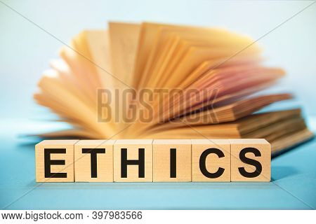Wooden Cubes With The Abbreviation Ethics On The Background Of An Open Book.
