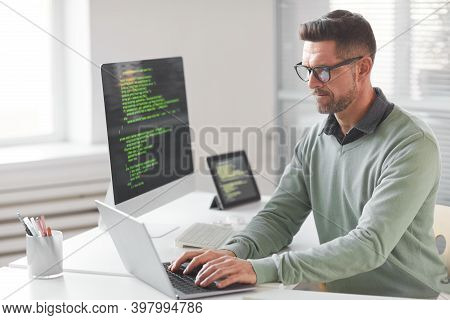Mature Computer Programmer Programming And Coding New Technologies While Typing On Laptop At The Tab