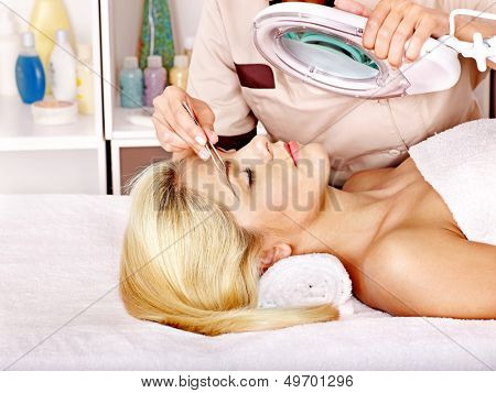 Vrouw krijgen tweezing wenkbrauw.