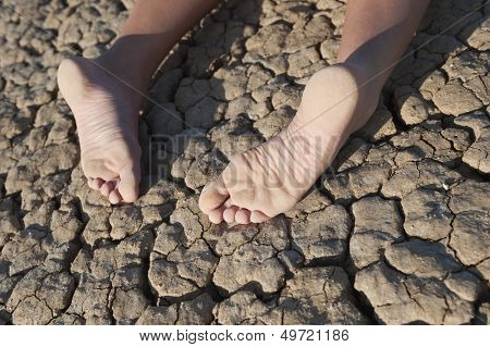 Low section of a woman lying on cracked land